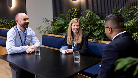 A group of Standard Chartered colleagues laugh together.