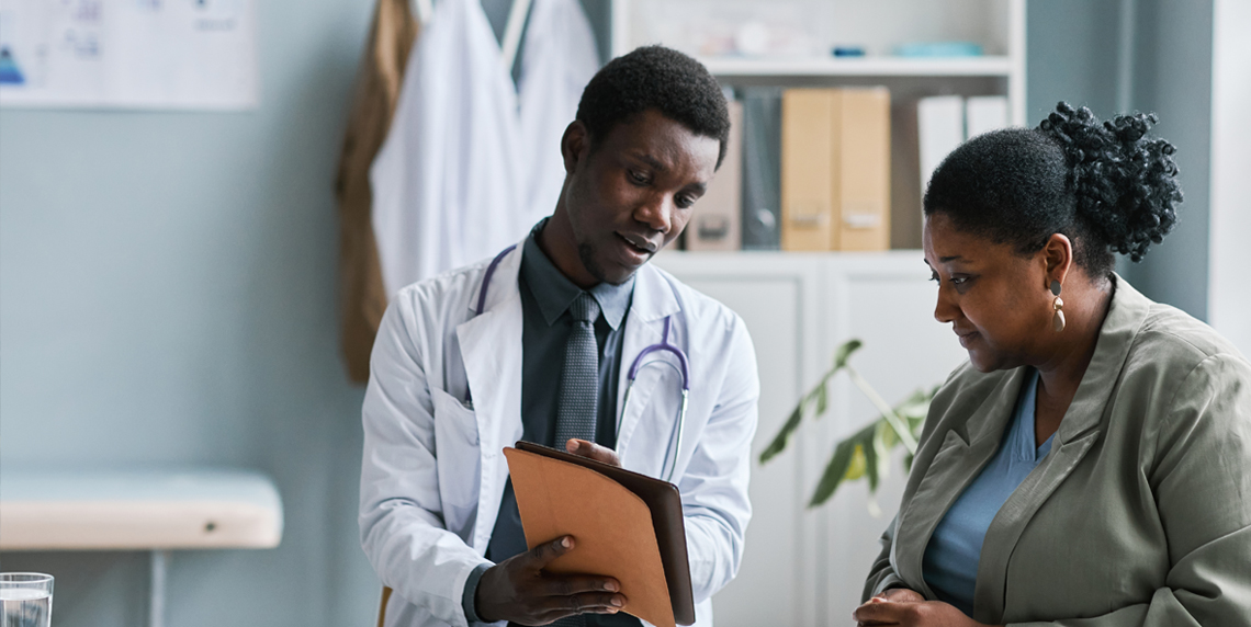 A doctor shows a woman patient information about her treatment for menopause-related symptoms in a folder.
