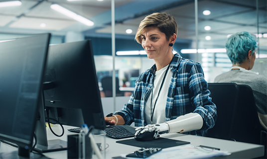 A woman with a prosthesis works on a computer.
