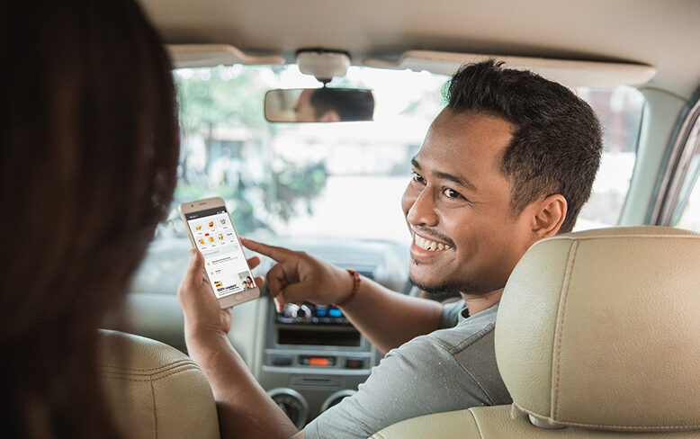 Asian driver looking back at passenger to chat