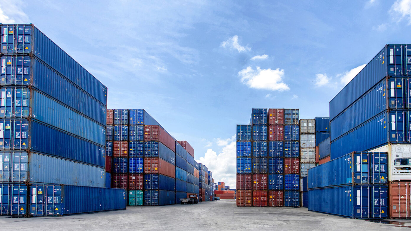 Blue shipping containers wait in a port