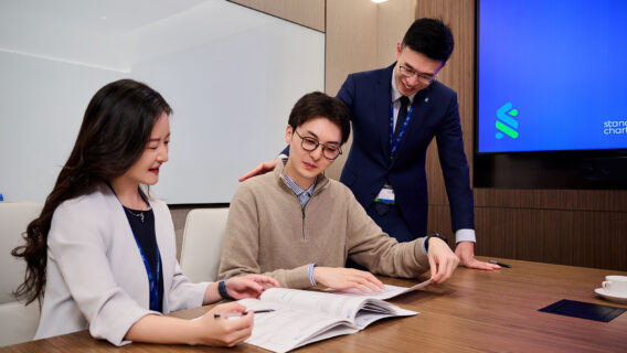 Three SC colleagues sitting at a table, working on a laptop.
