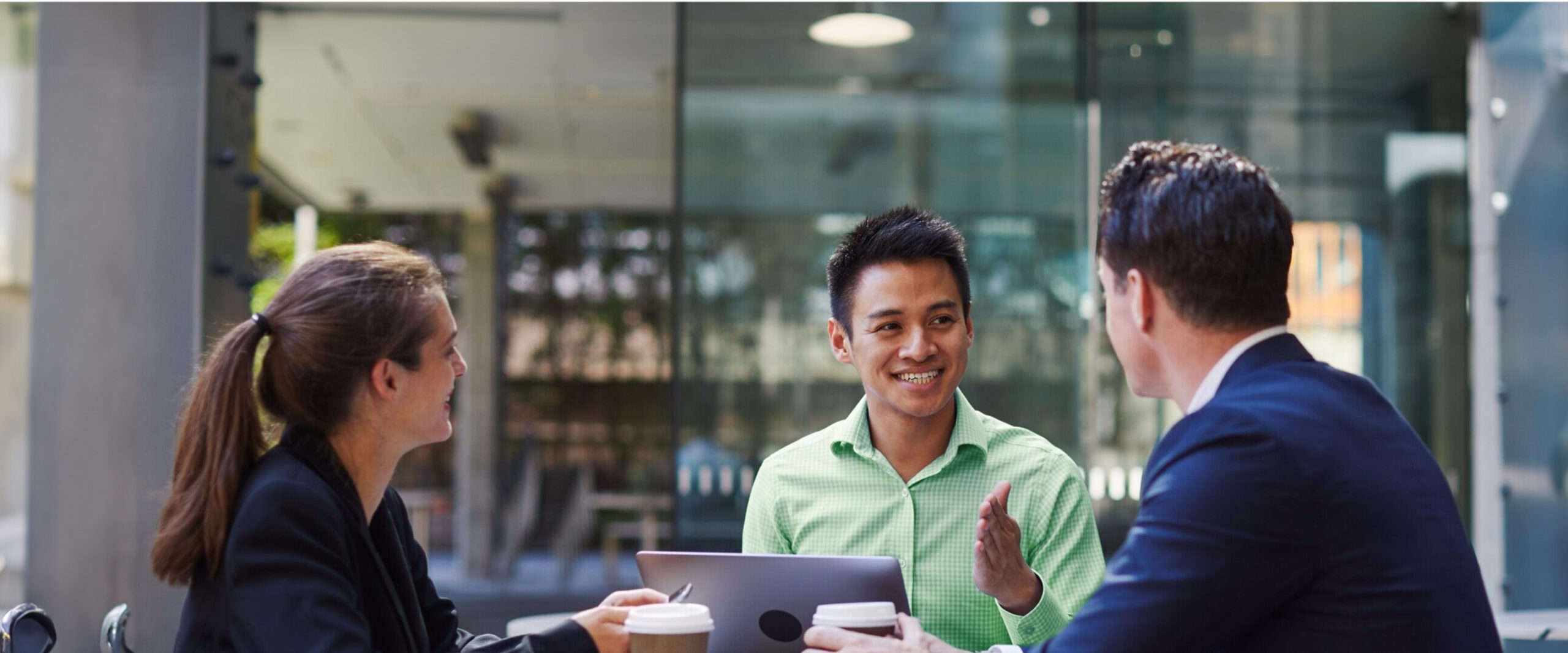 A group of colleagues have a discussion over a coffee with a laptop.