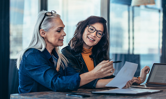 Two senior women work on a report together.