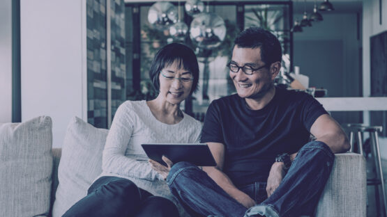 Couple smiling at tablet sitting together
