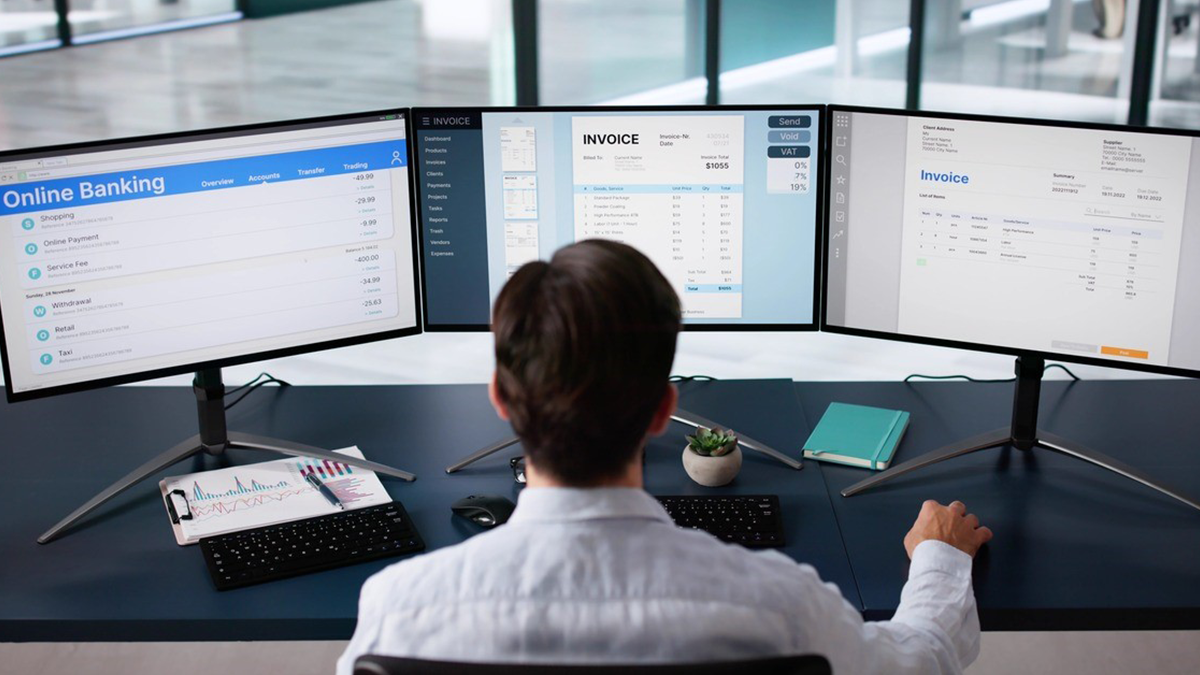 Man working in front of 3 computer screens