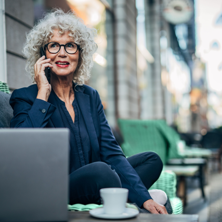 A financier takes a phone call in front of her laptop at a cafe.